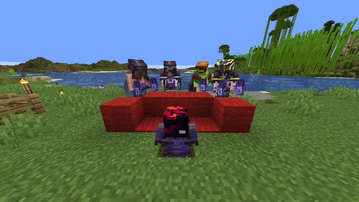 Players gathered around a red wool couch beside a lake